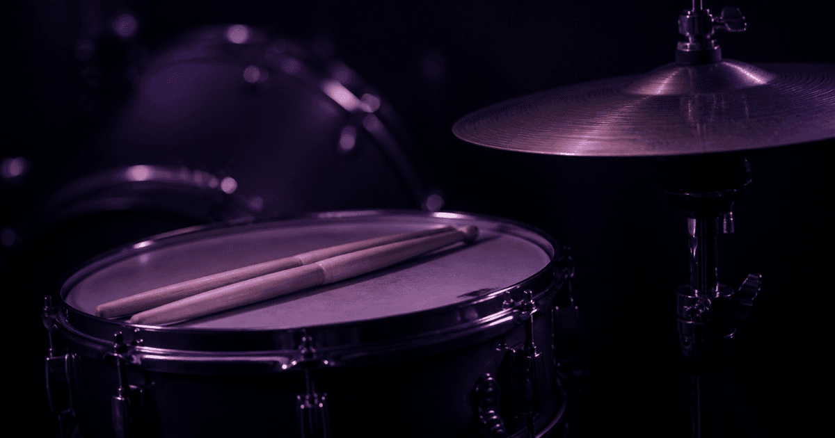 Snare drum and hi-hat with drumsticks lit in deep purple studio shadow